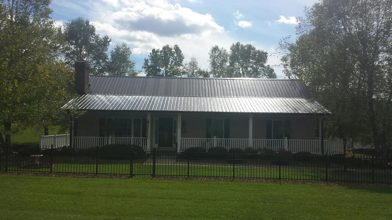 Gray metal roof on a brick ranch with a full width front porch — Gutter Guard Installation work by our crew in Antonito