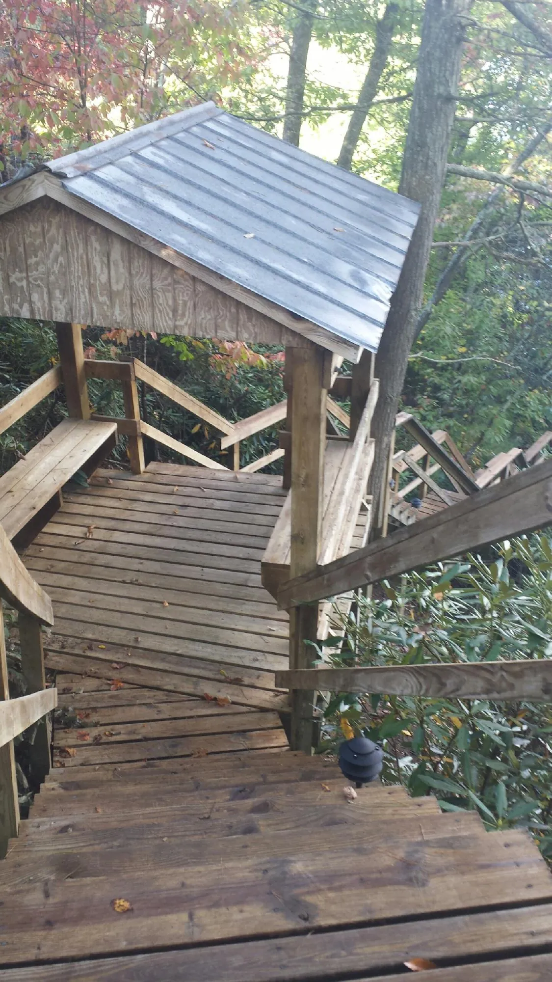 Metal roofed shelter over wooden steps on a wooded walkway — Skylight Repair & Installation work by our crew in Antonito
