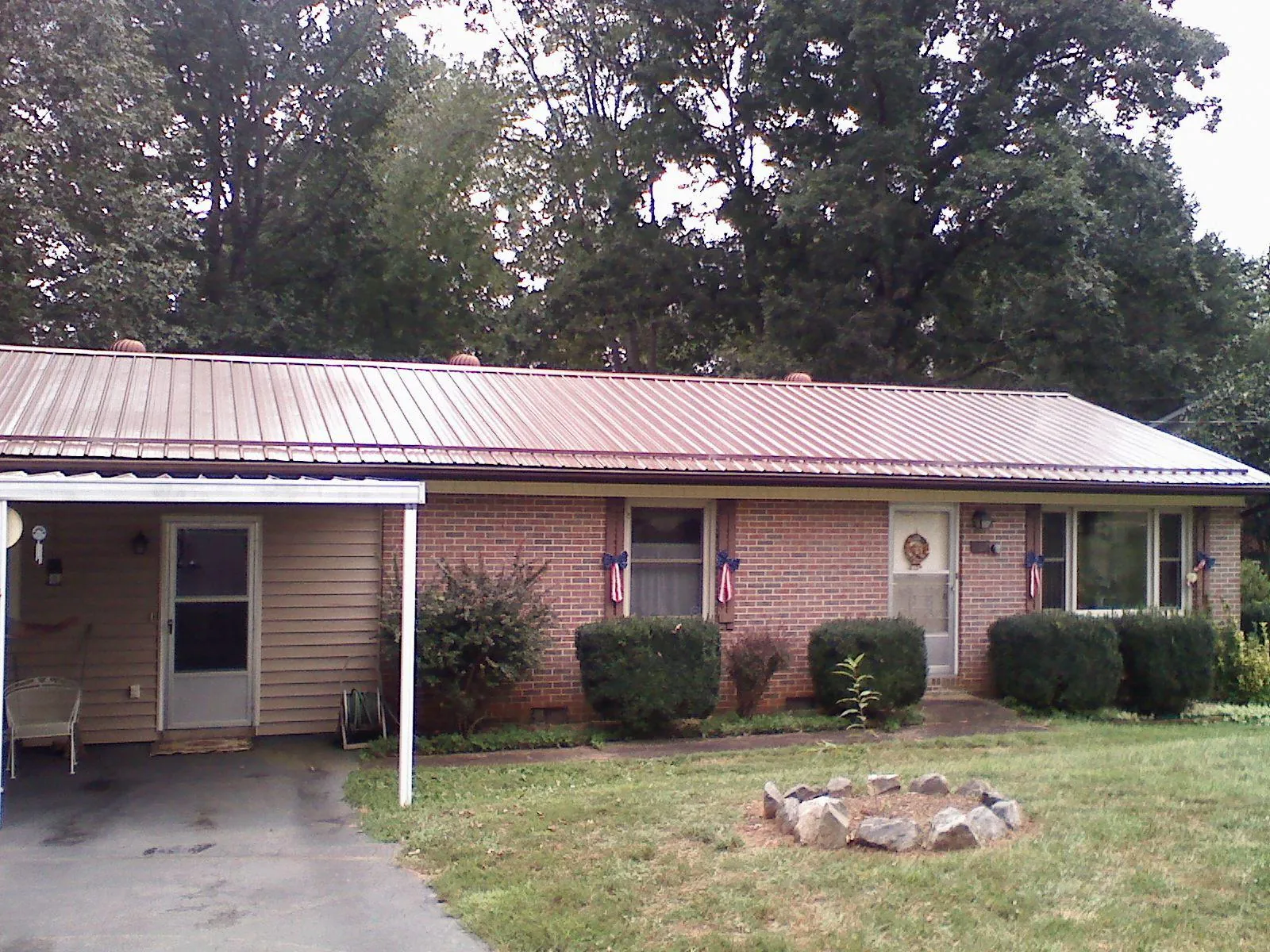 Bronze metal roof and carport on a brick ranch home — Roof Repair work by our crew in Antonito