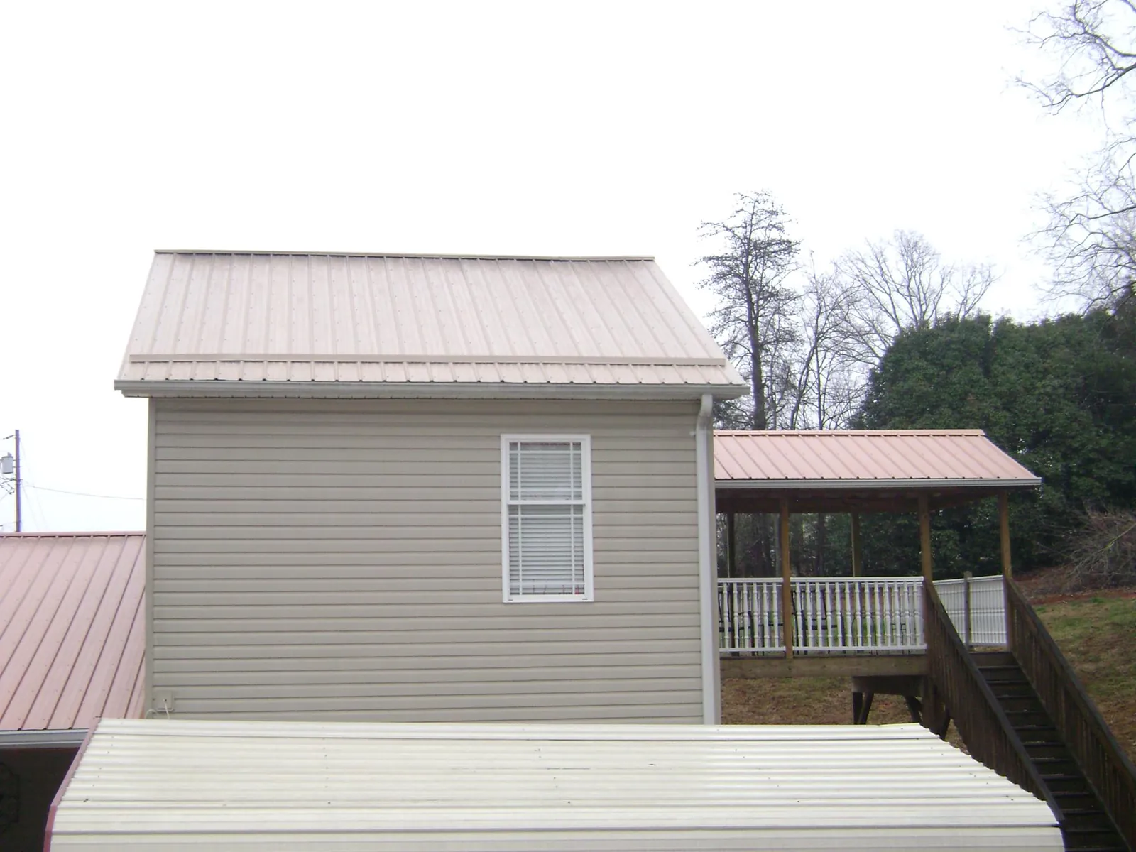 Tan metal roofs on a two story addition and attached porch, from a Roof Replacement job in Antonito