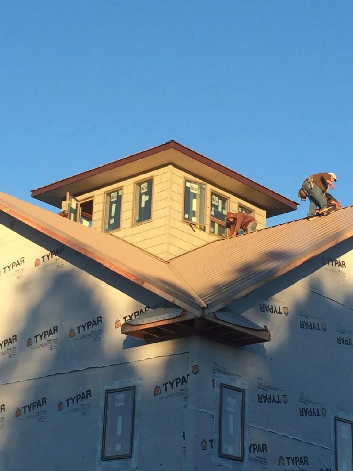 Roofers working around a rooftop cupola on a new metal roof at sunset — Roof Waterproofing in Antonito by Roofing Brothers